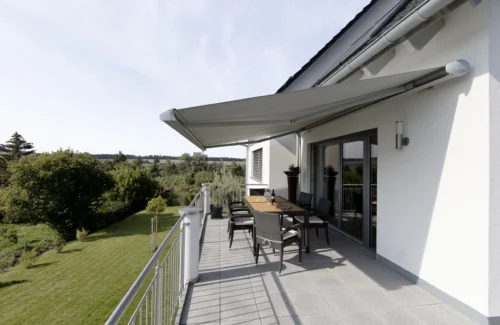 Moderne Terrasse mit Markise und Sitzbereich im Grünen