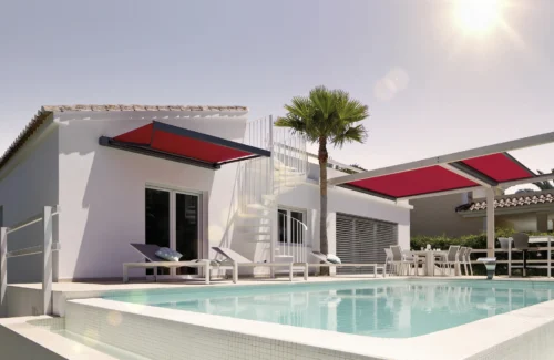Moderne Villa mit Pool und roten Markisen bei Sonnenschein