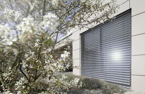 Moderne Architektur mit blühenden Bäumen und Sonnenschutz