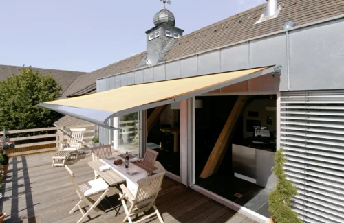 Terrasse mit Markise und Gartenmöbeln an einem sonnigen Tag